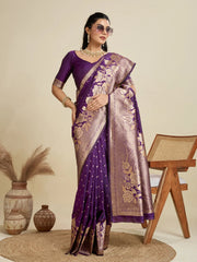 Woman wearing a purple saree with gold patterns in a minimalistic setting.