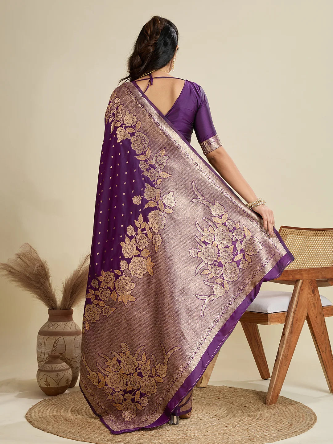 Woman wearing a purple saree with floral patterns in a minimalistic setting