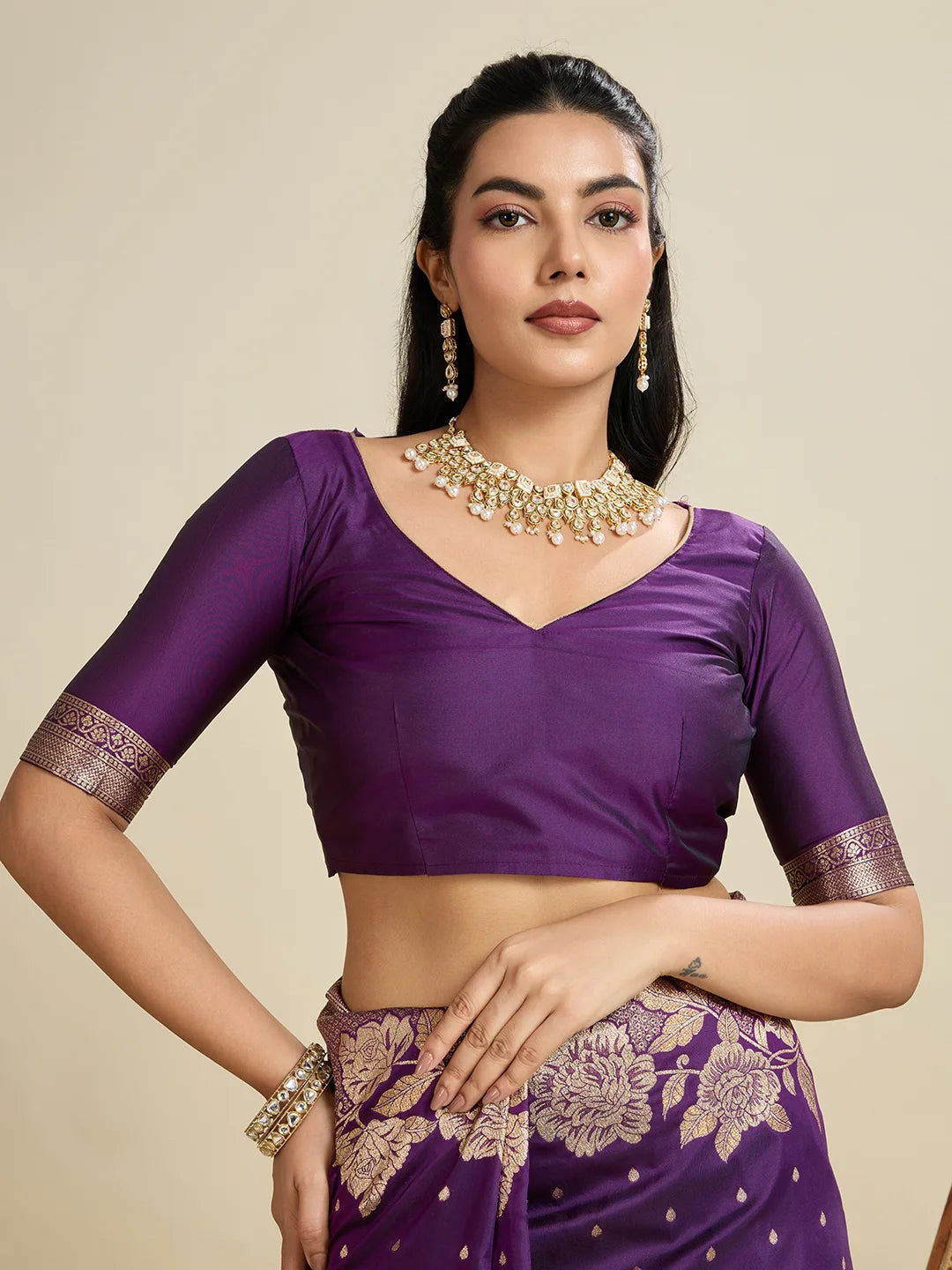 Woman wearing a purple traditional outfit with gold embroidery on a beige background