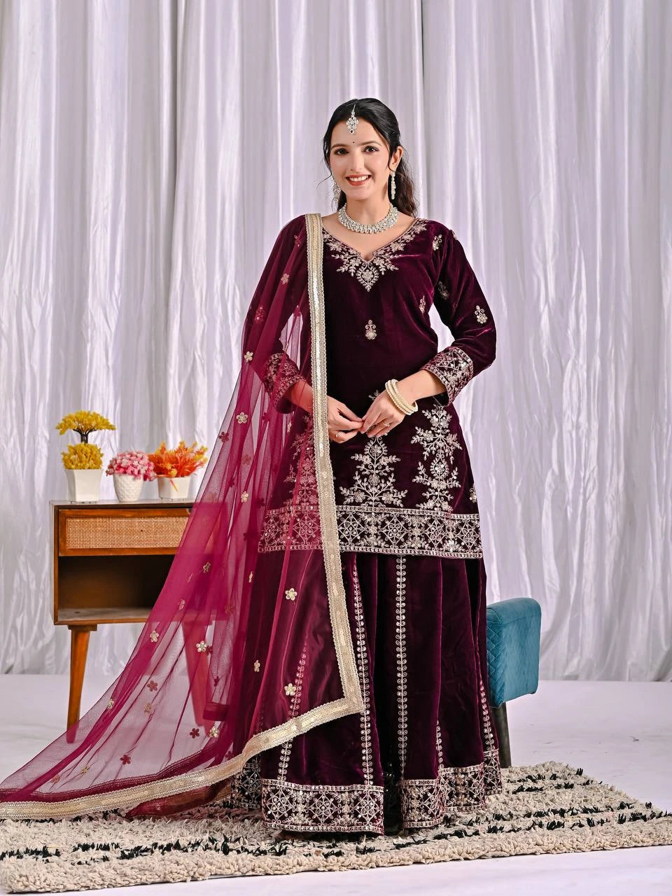 Woman in a maroon embroidered traditional outfit with a white background