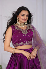 Woman wearing a purple traditional outfit with jewelry against a white background