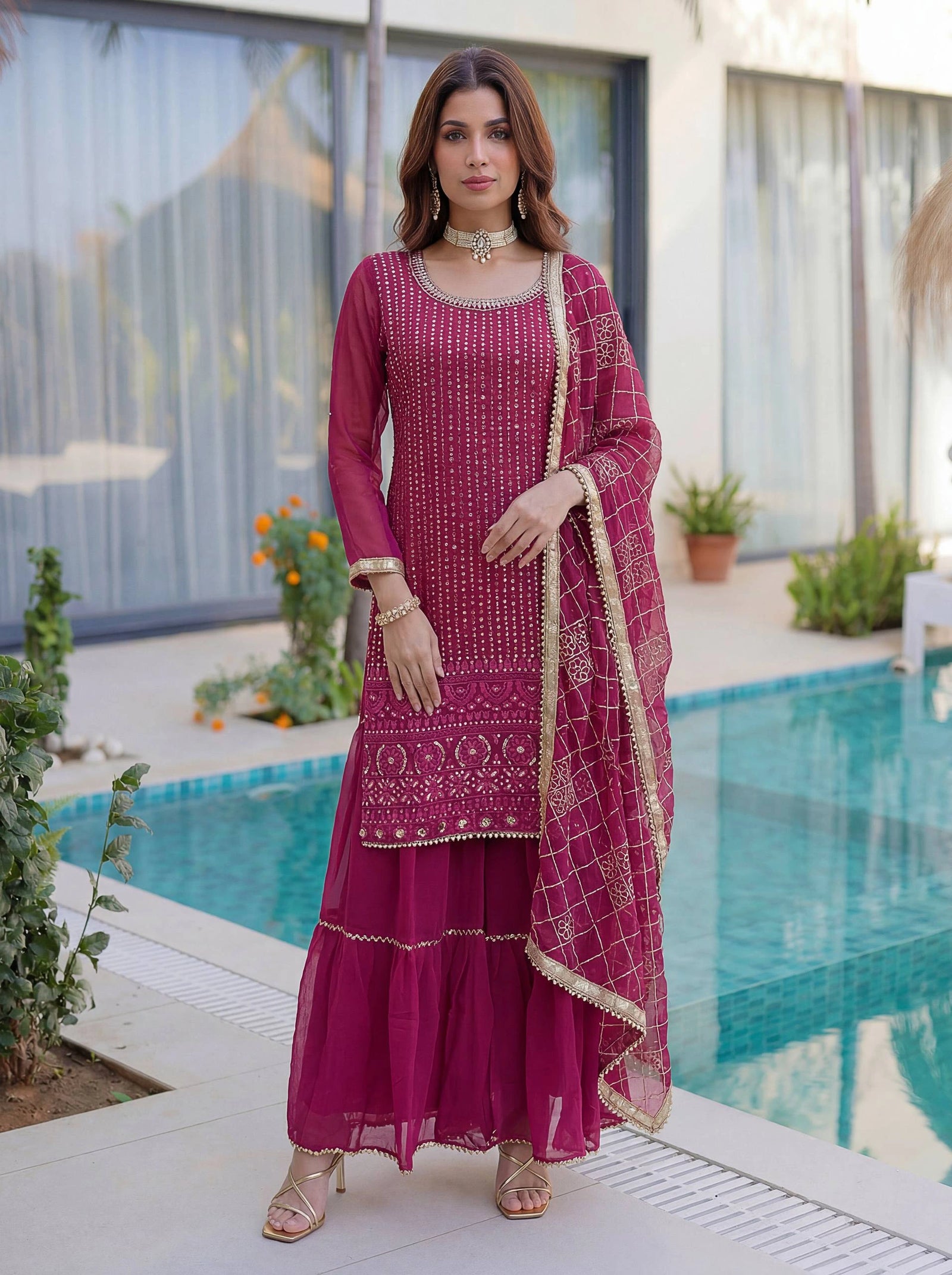 Woman in a pink traditional outfit standing by a pool