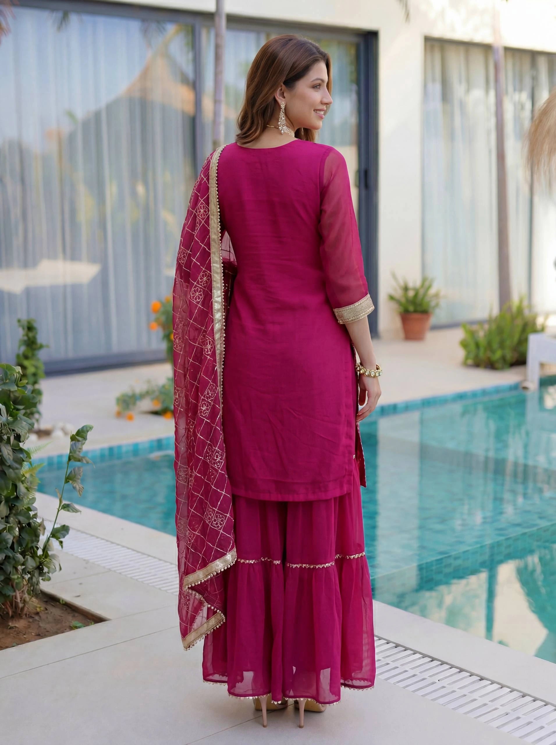Woman in a pink traditional outfit standing by a pool