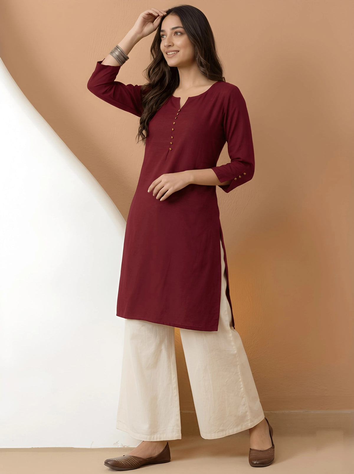 Woman wearing a maroon kurta with white pants against a beige background