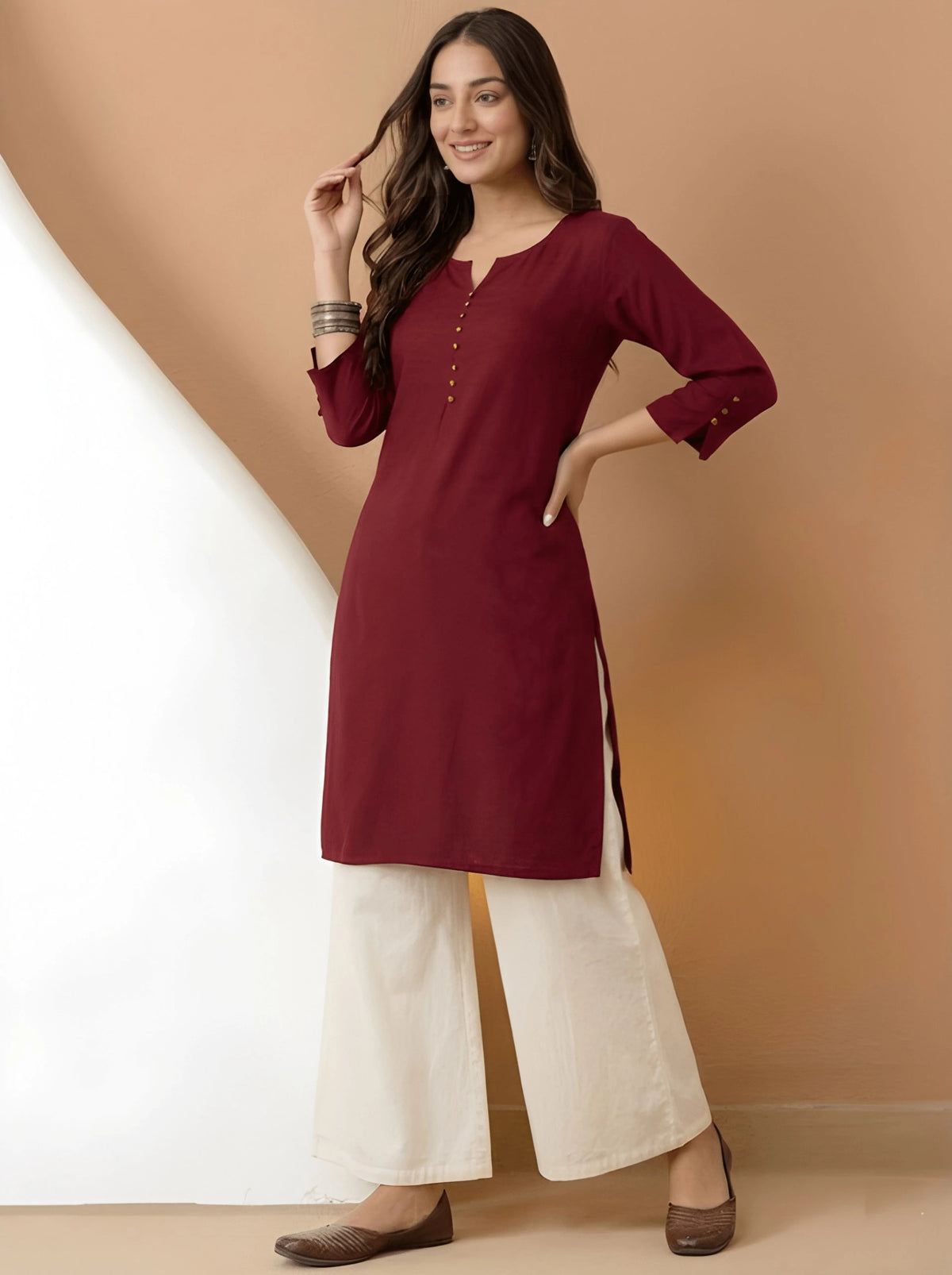 Woman wearing a maroon kurta with white palazzo pants against a beige background