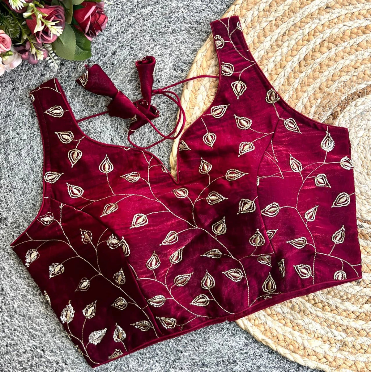 Maroon embroidered outfit with floral decorations on a textured surface