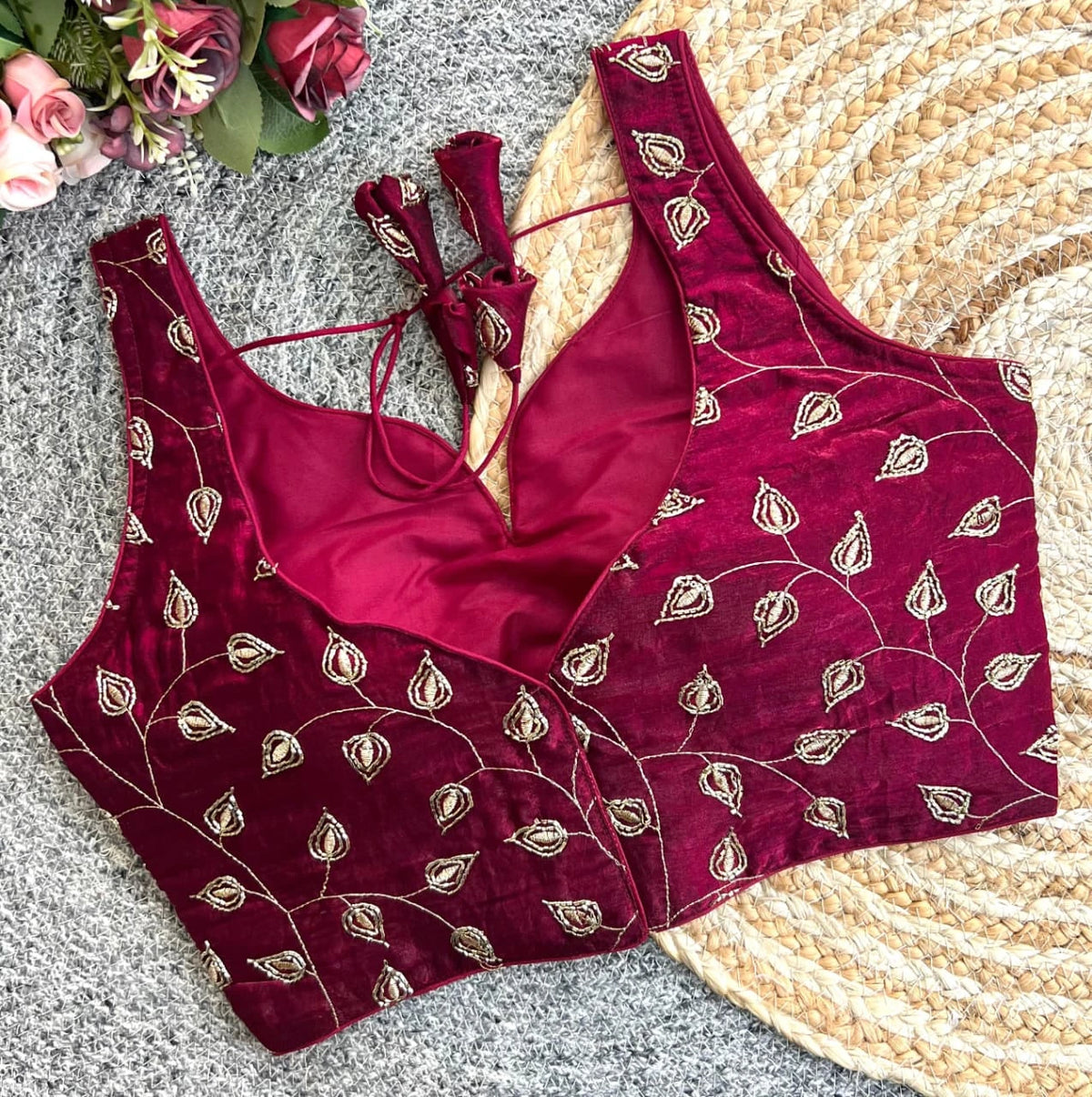 Maroon embroidered blouse with matching pants on a textured surface with flowers.
