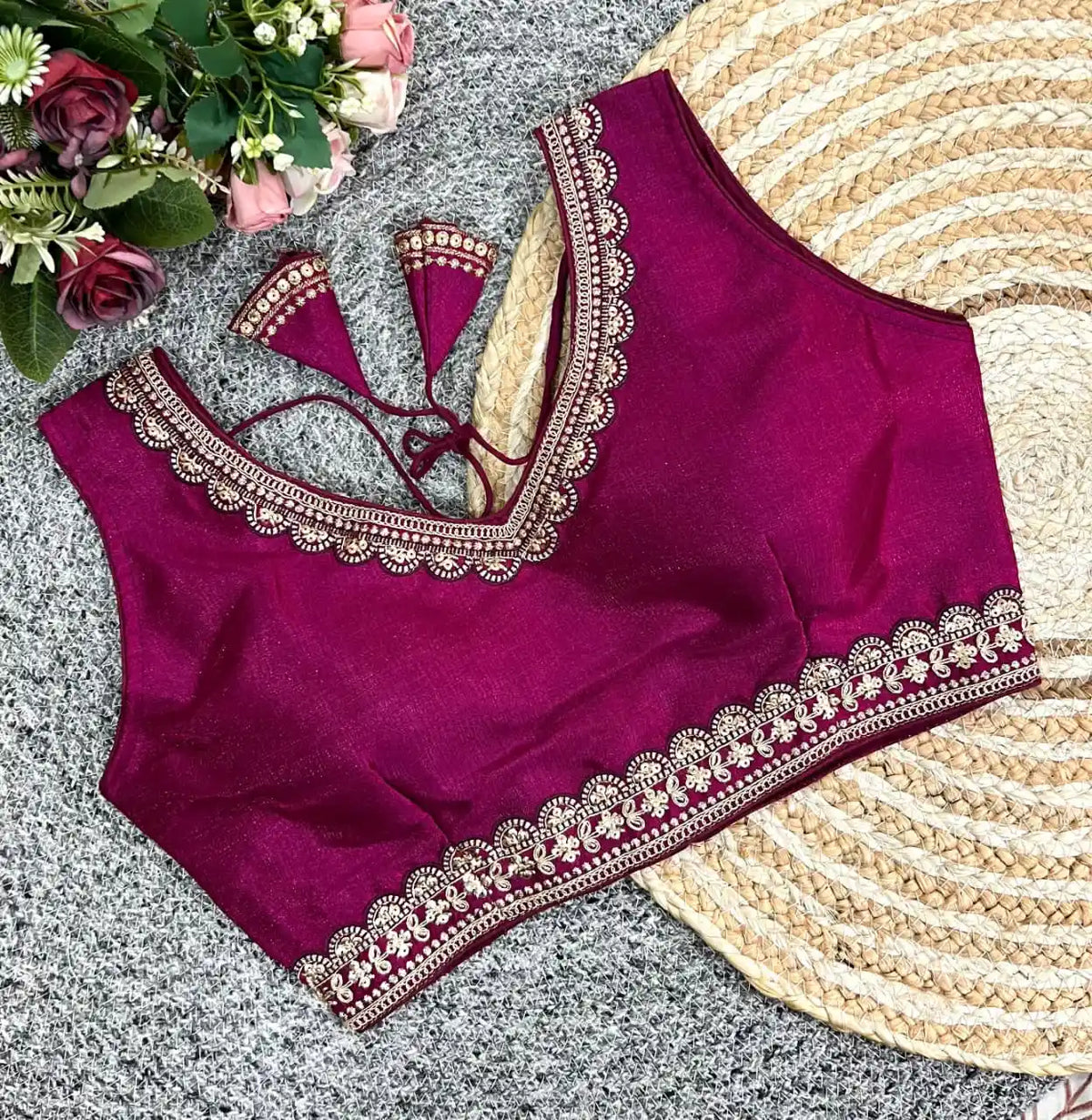 Purple blouse with intricate gold embroidery on a textured surface with flowers.