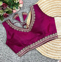 Purple blouse with intricate gold embroidery on a textured surface with flowers.