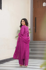 Woman in a pink traditional outfit standing in front of a building entrance.
