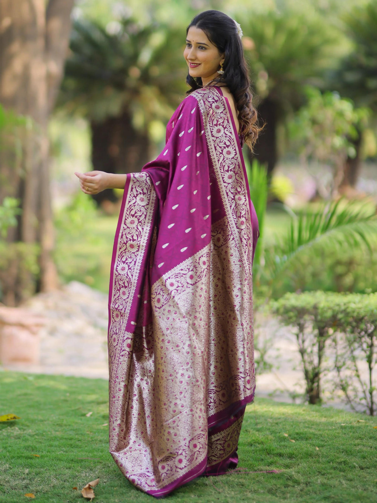 Woman wearing a purple and beige saree in a garden setting