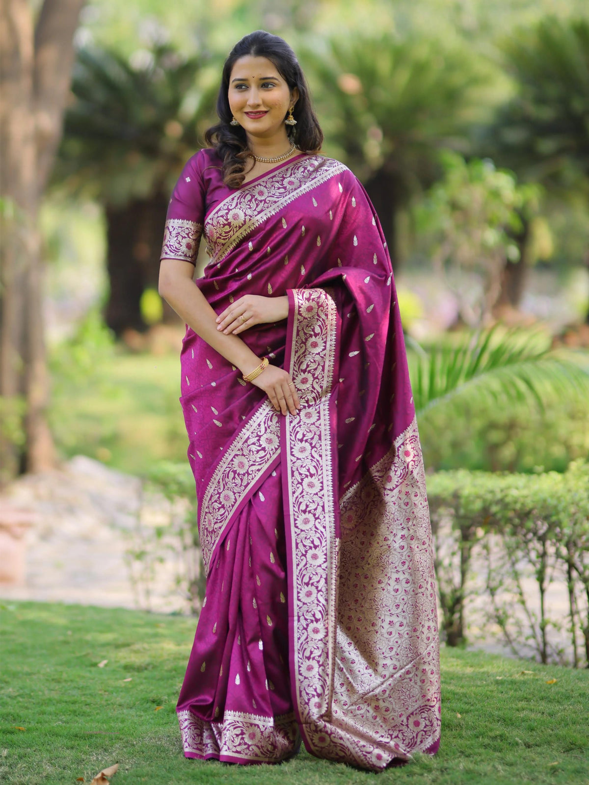 Woman wearing a purple saree with a garden background