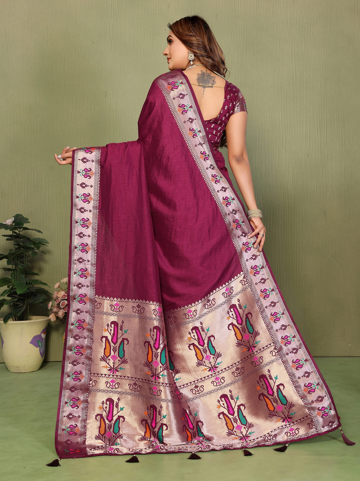 Woman wearing a traditional saree with intricate patterns on a green background