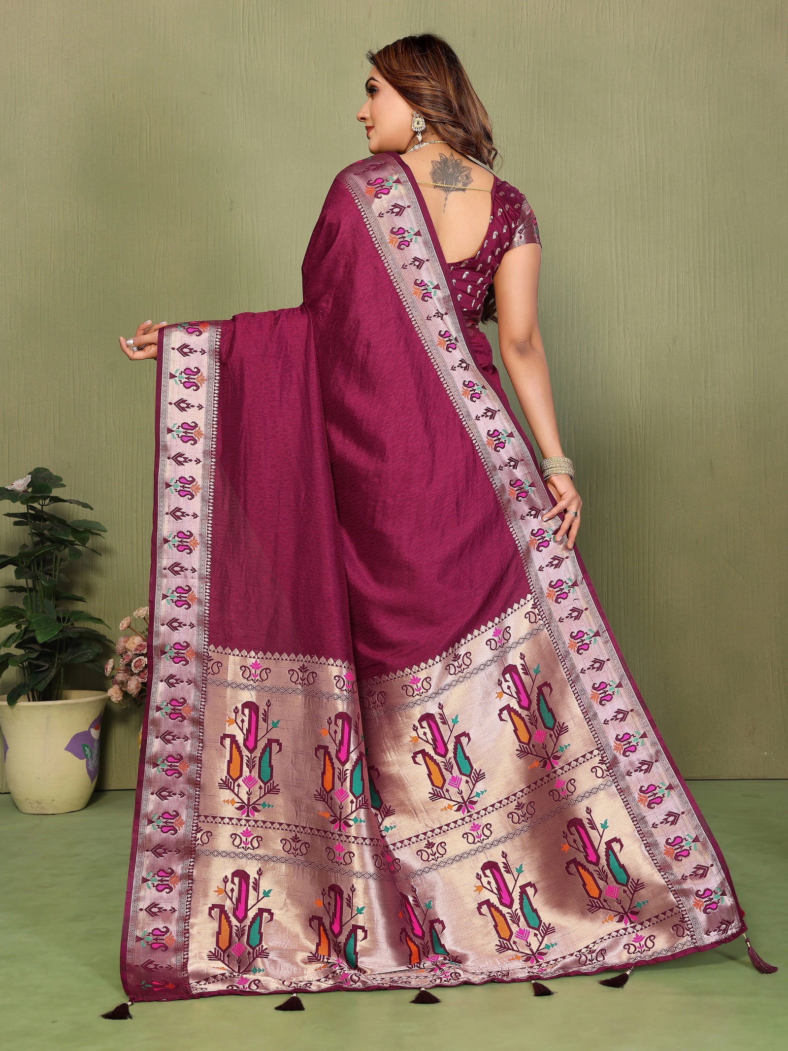 Woman wearing a traditional saree with intricate patterns on a green background