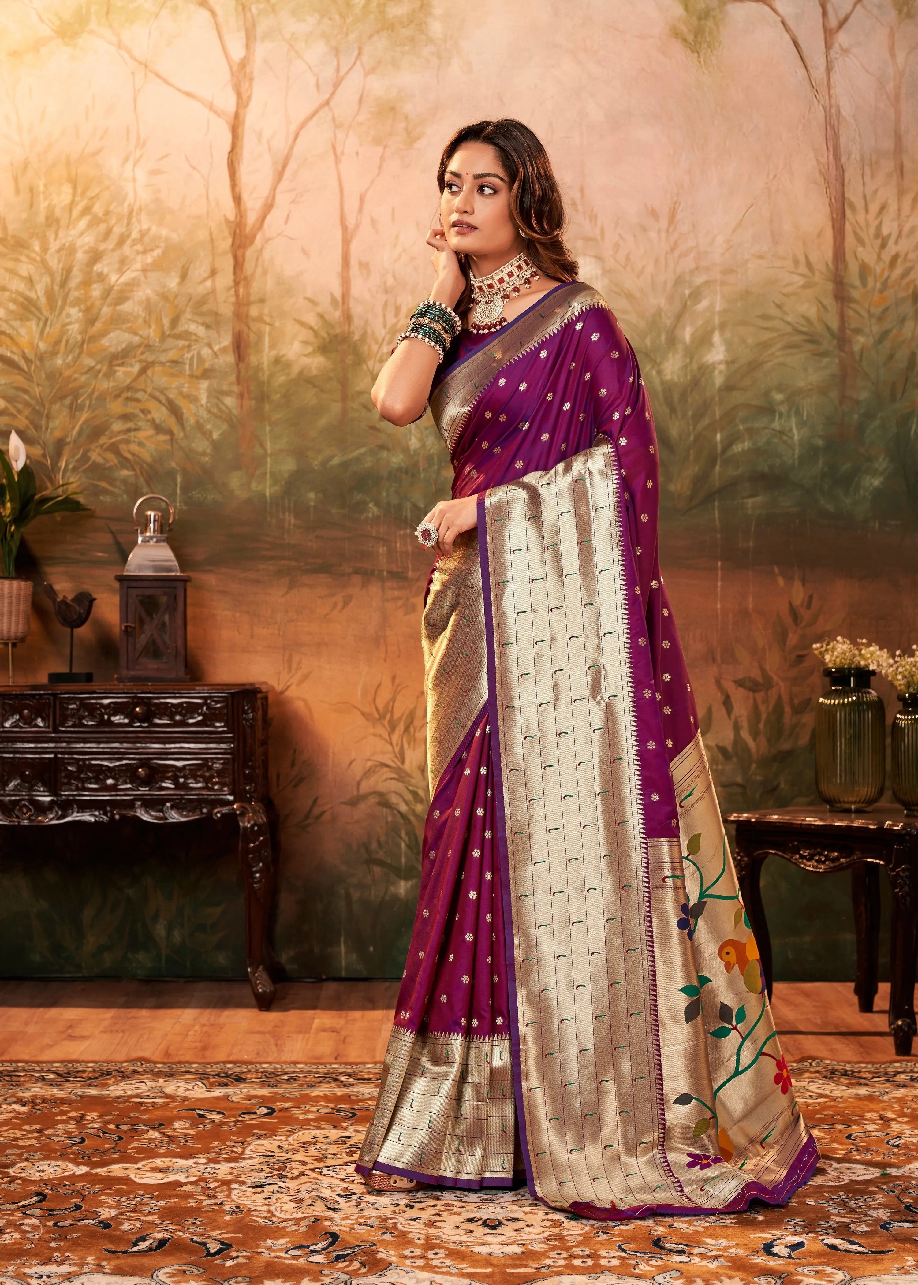 Woman in a purple and beige saree with floral patterns in an indoor setting.