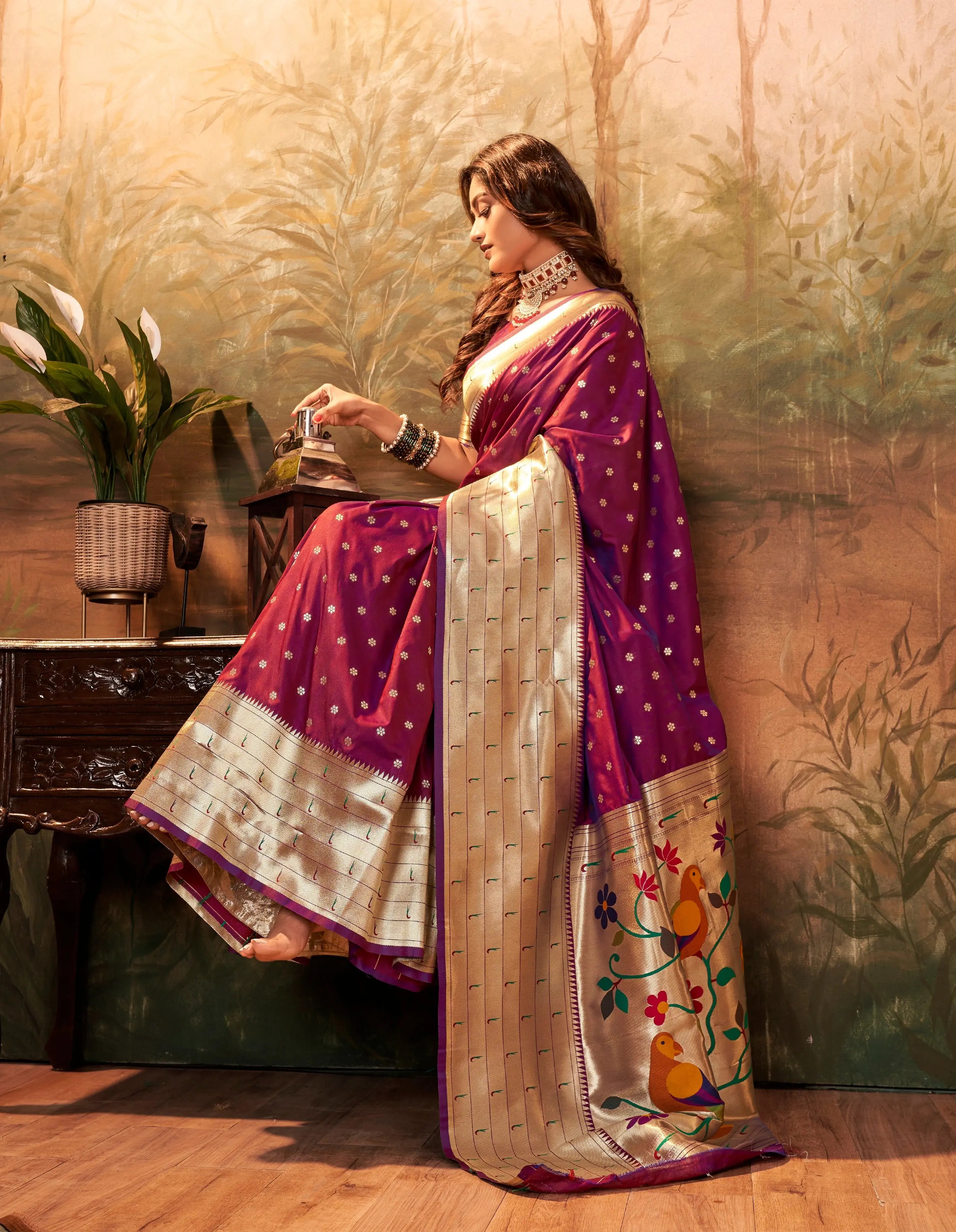 Woman in a traditional saree sitting in a room with decorative elements.