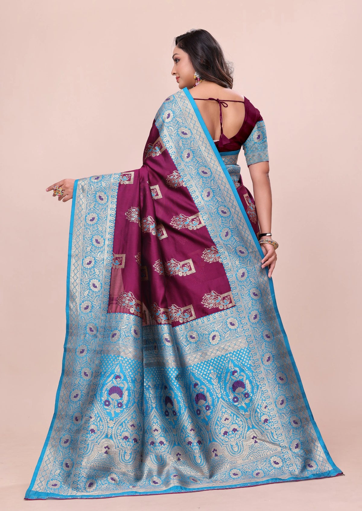 Woman wearing a purple and blue saree with a pink background