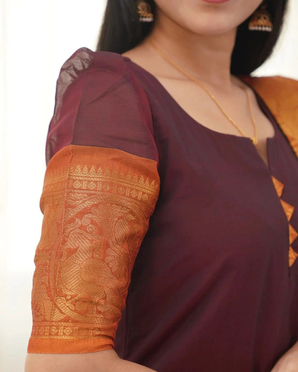 Close-up of a maroon and orange traditional outfit with intricate patterns.
