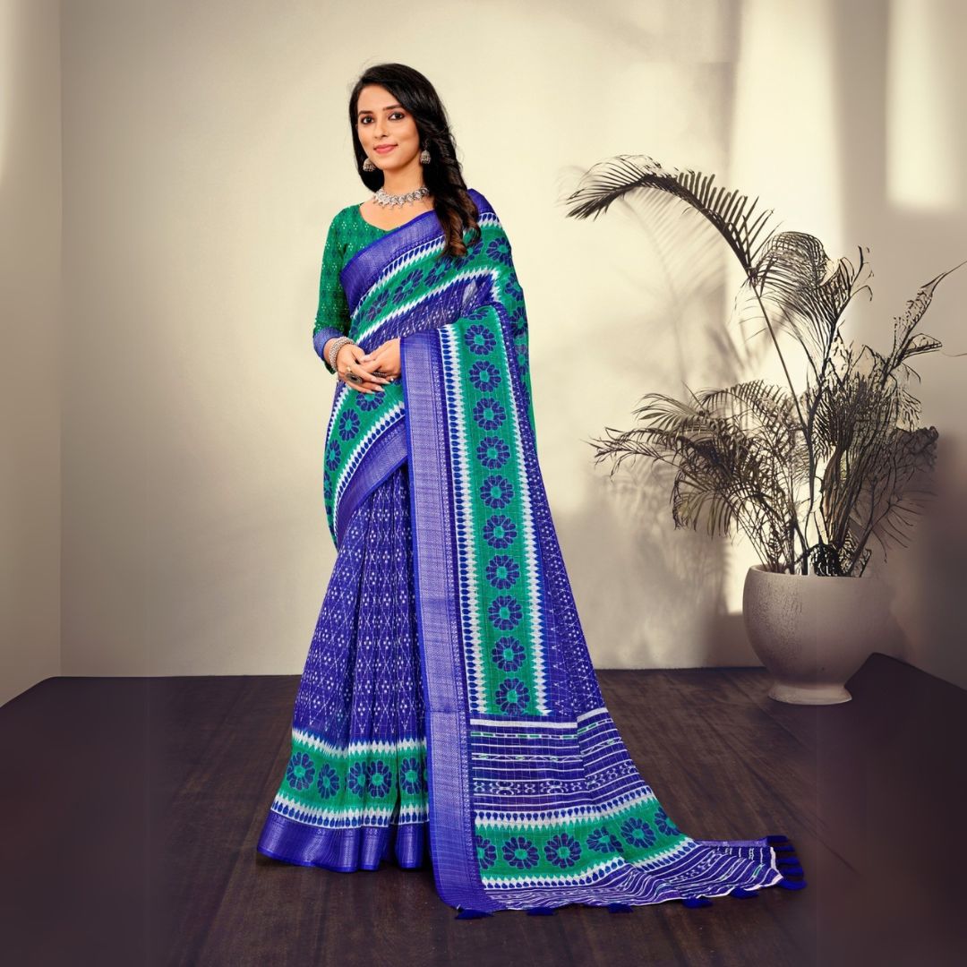 Woman in a traditional navy blue saree with printed patterns standing indoors near a potted plant