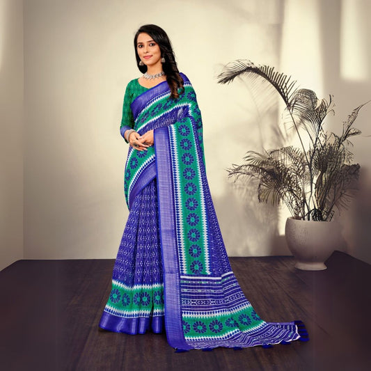 Woman in a traditional navy blue saree with printed patterns standing indoors near a potted plant