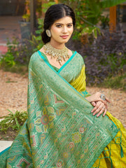 Woman wearing a green and yellow saree with floral patterns outdoors.