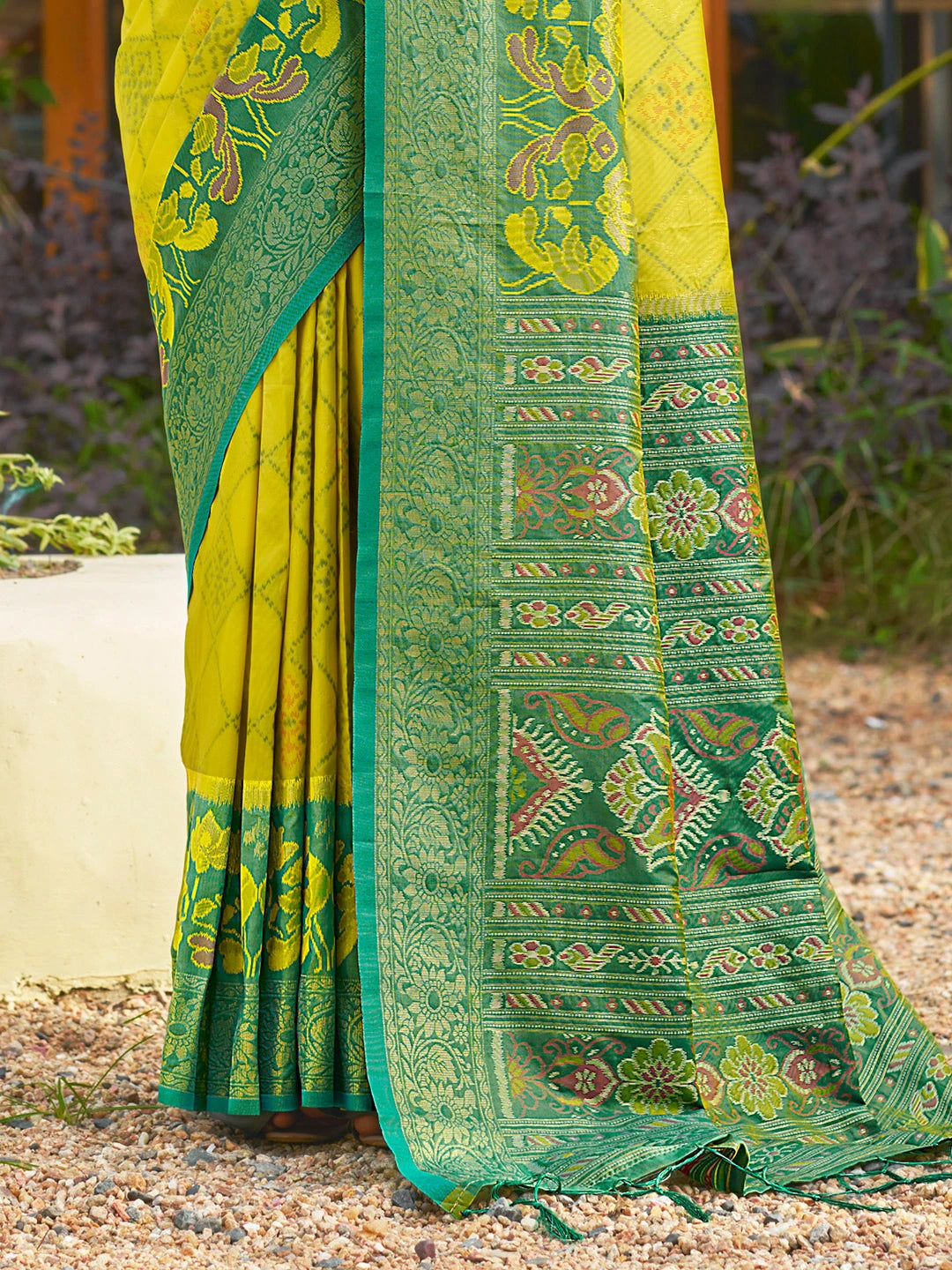 Green and yellow saree with intricate patterns on a natural background