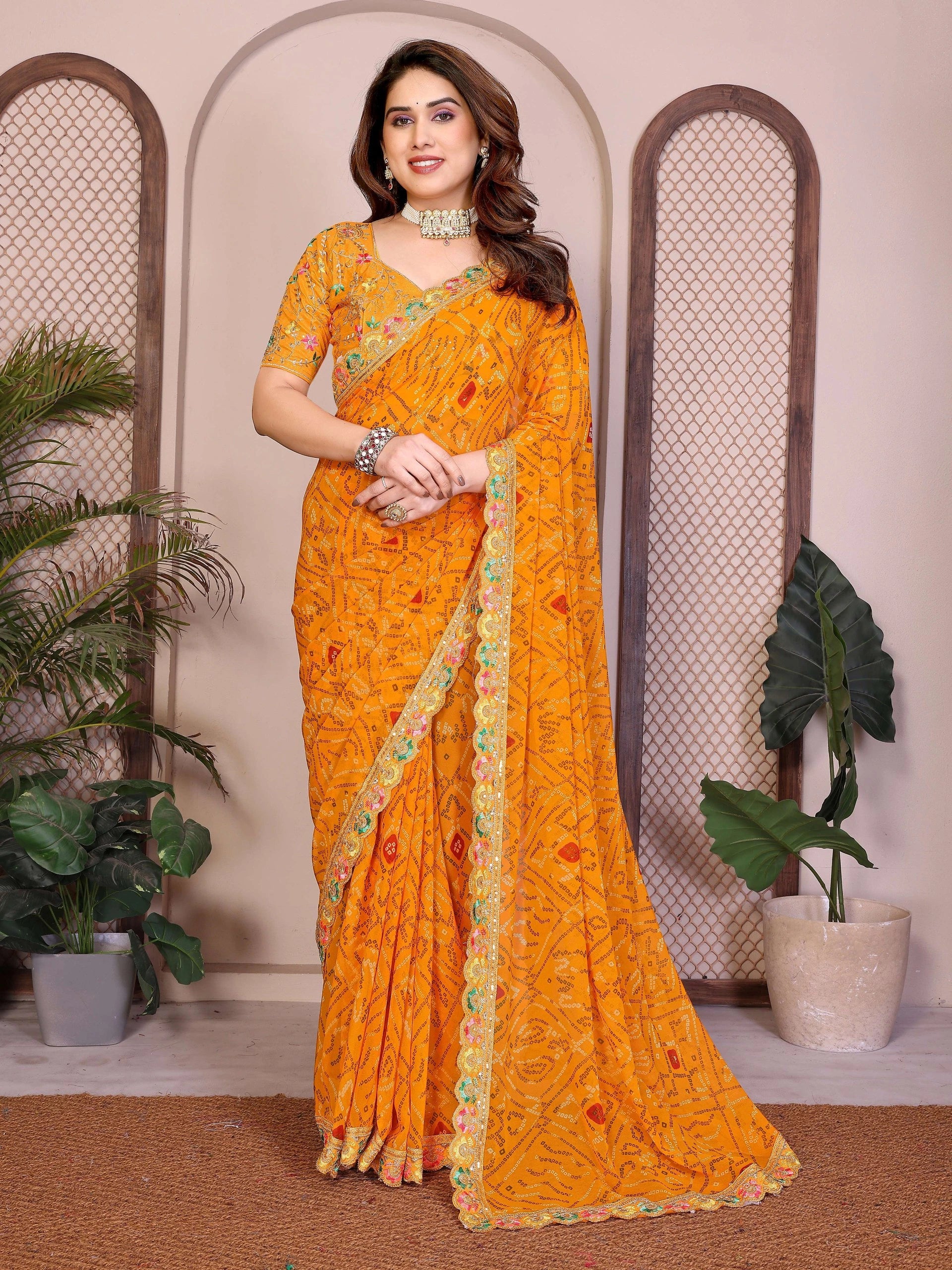 Woman wearing a bright orange saree with a decorative border indoors.