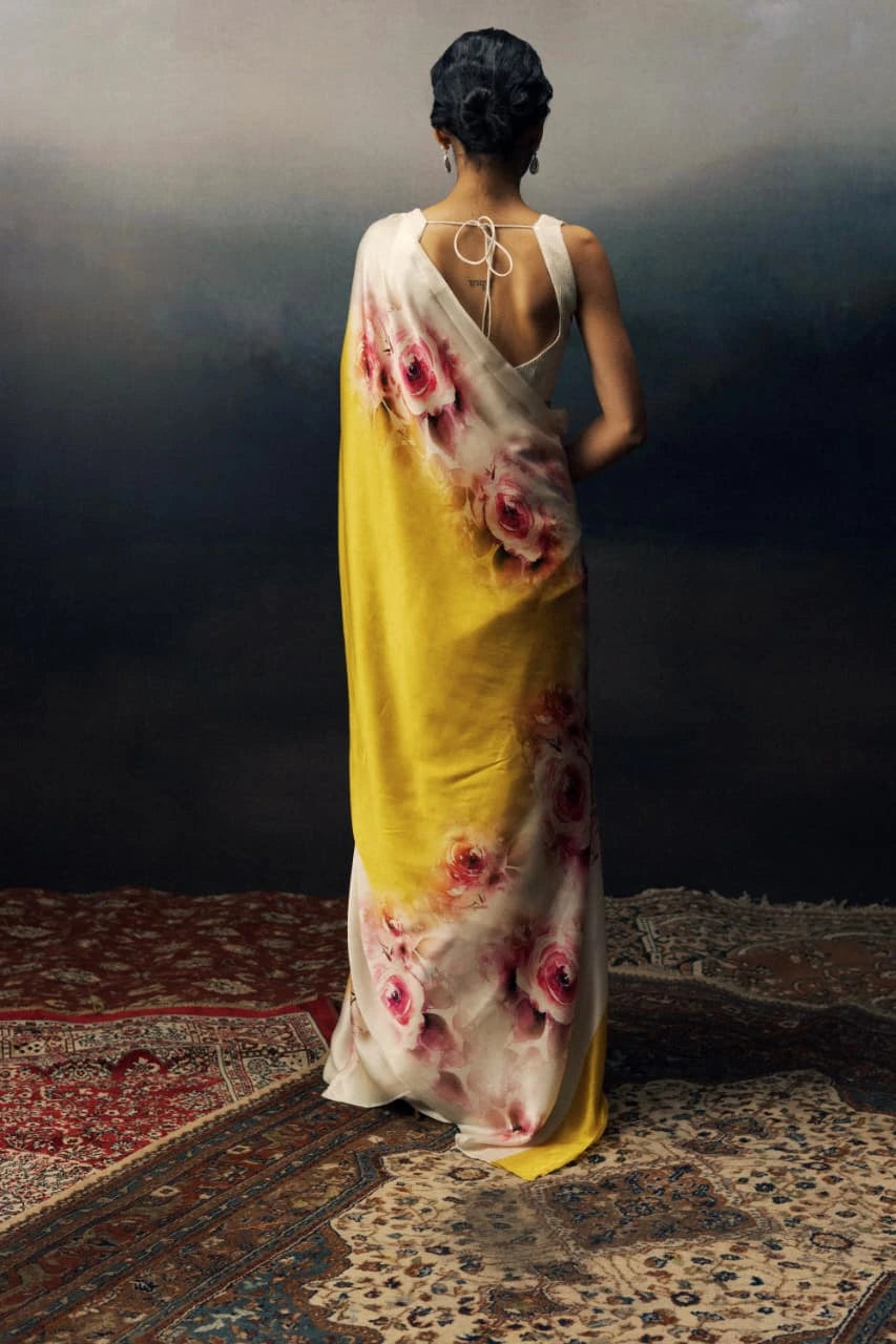 Woman wearing a floral dress with a yellow base, standing on a textured floor.