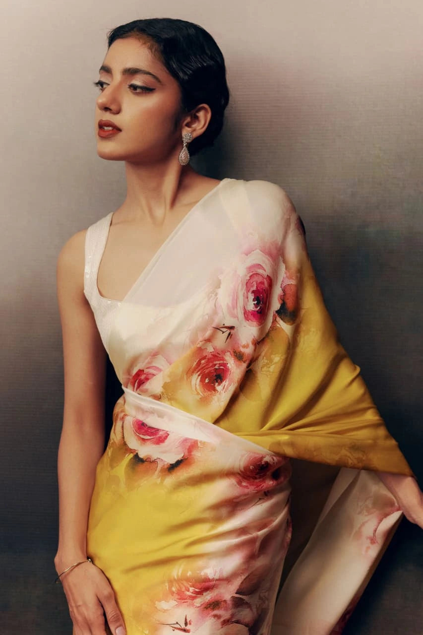 Woman wearing a floral saree against a plain background