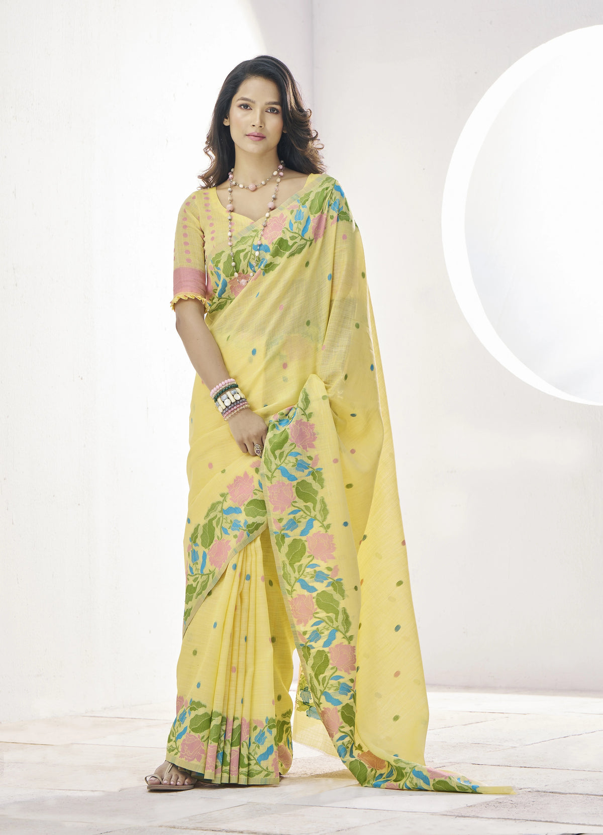 Woman wearing a yellow saree with floral patterns on a white background