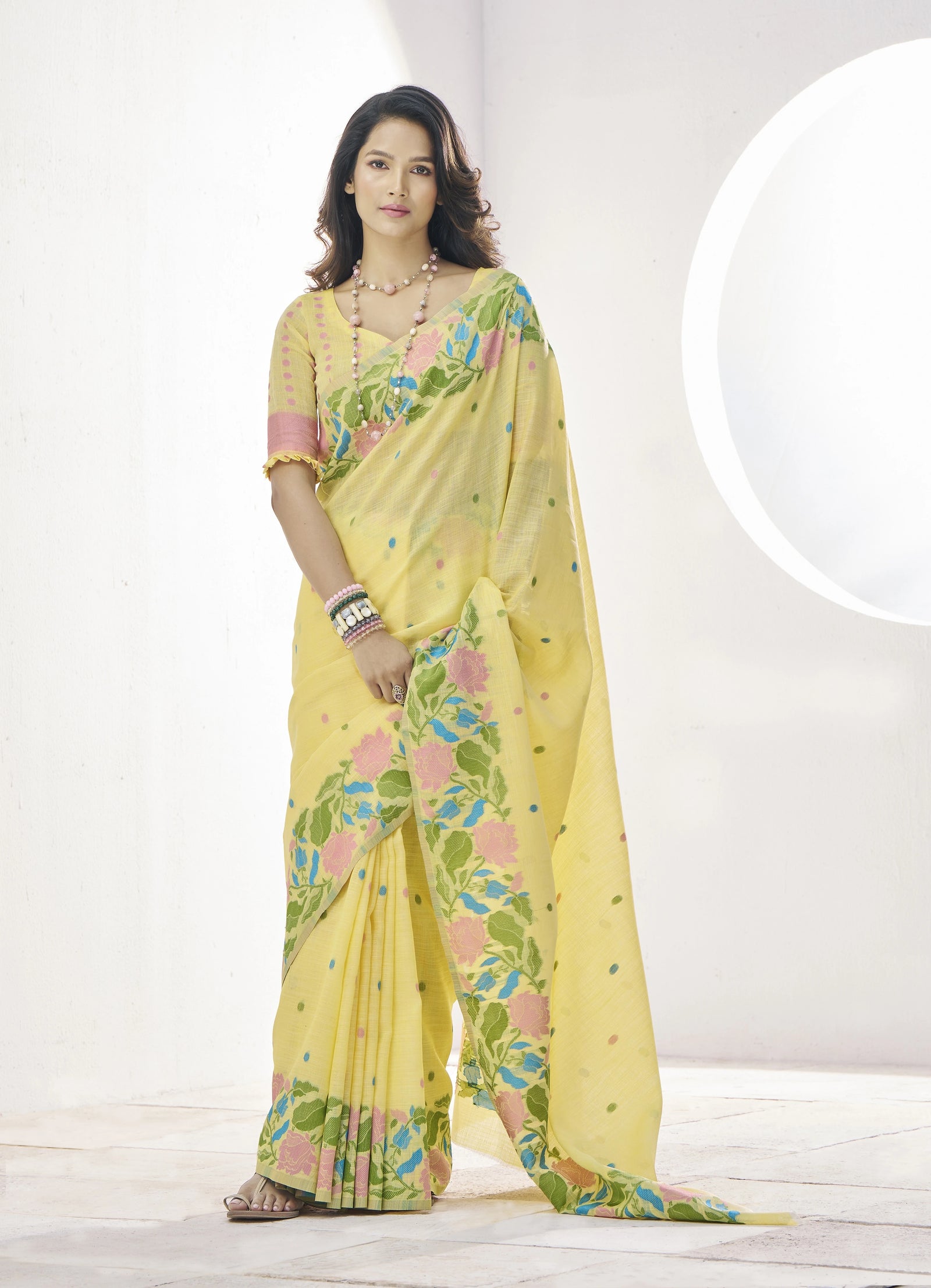 Woman wearing a yellow saree with floral patterns on a white background
