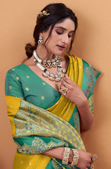 Woman wearing a green and yellow saree with jewelry against a beige background