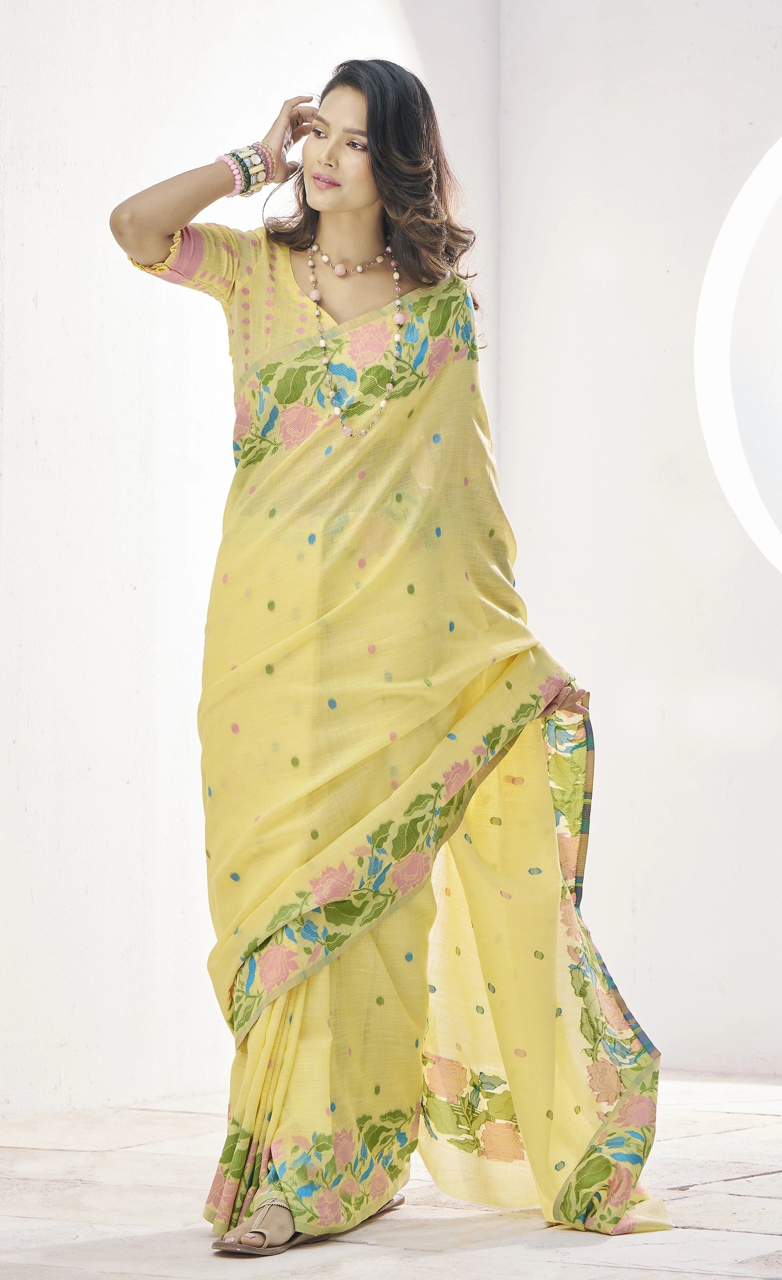 Woman wearing a yellow saree with floral patterns on a white background
