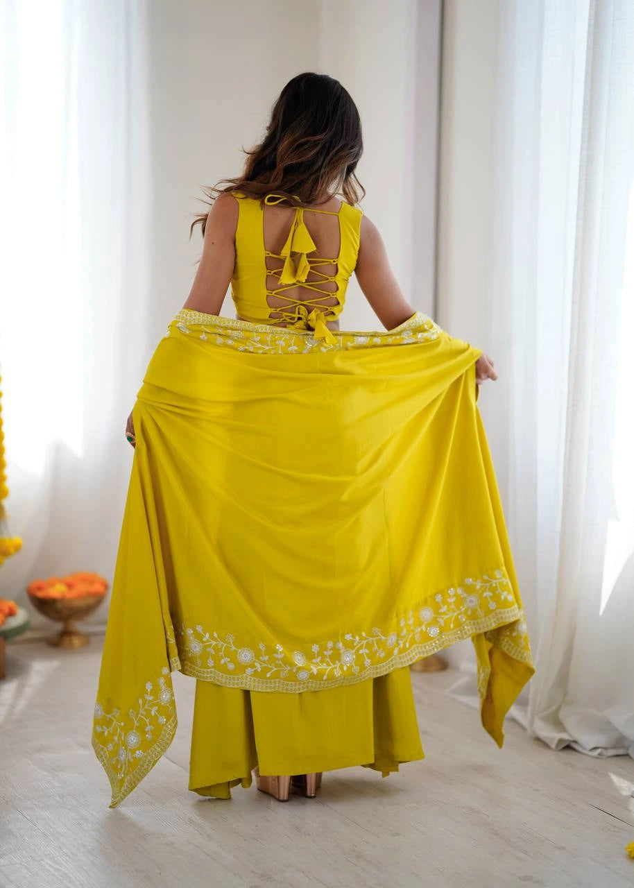 Woman wearing a yellow traditional outfit with a floral pattern in a bright room.