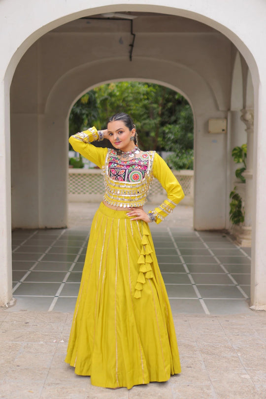 Woman in a yellow traditional outfit standing under an archway.