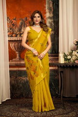 Woman in a yellow saree with floral patterns standing indoors.