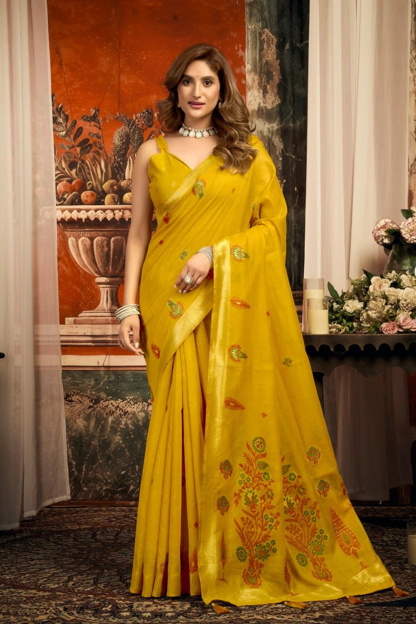 Woman wearing a yellow saree with floral patterns in an indoor setting.