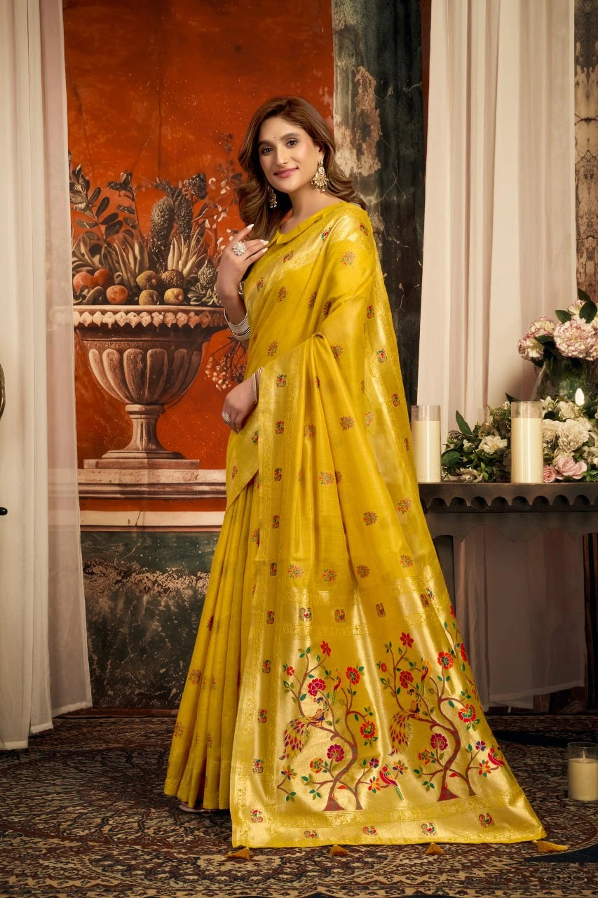 Woman in a yellow saree with floral patterns in an indoor setting.