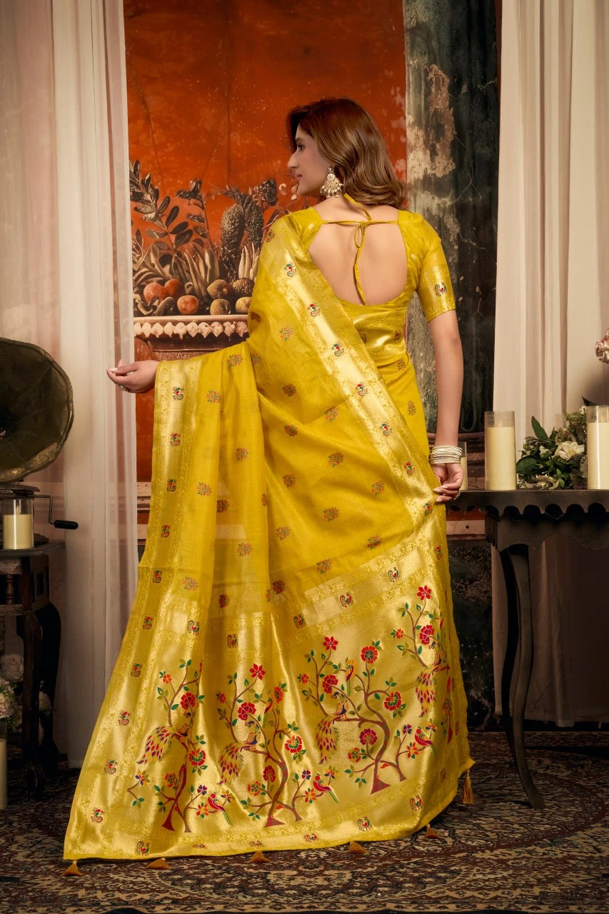 Woman in a yellow saree with floral patterns standing indoors.