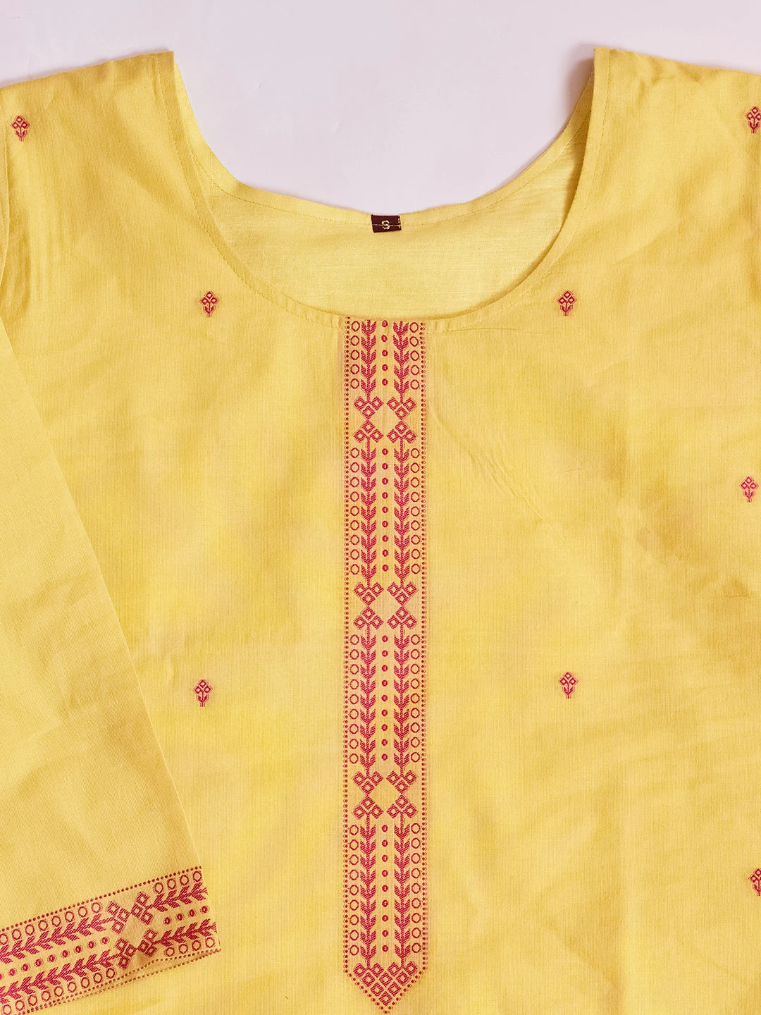Yellow sleeveless top with red embroidery on a white background