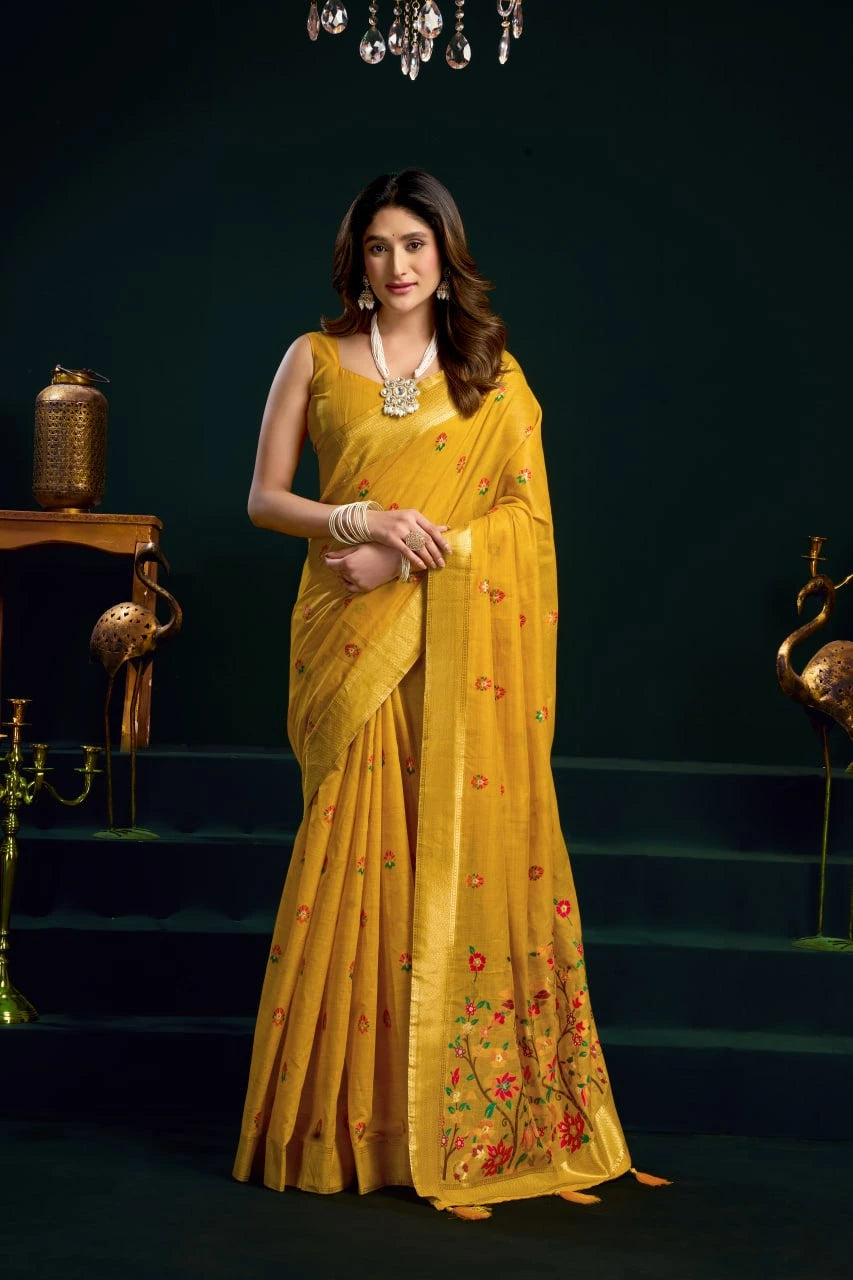 Woman in a yellow saree with floral patterns against a dark background