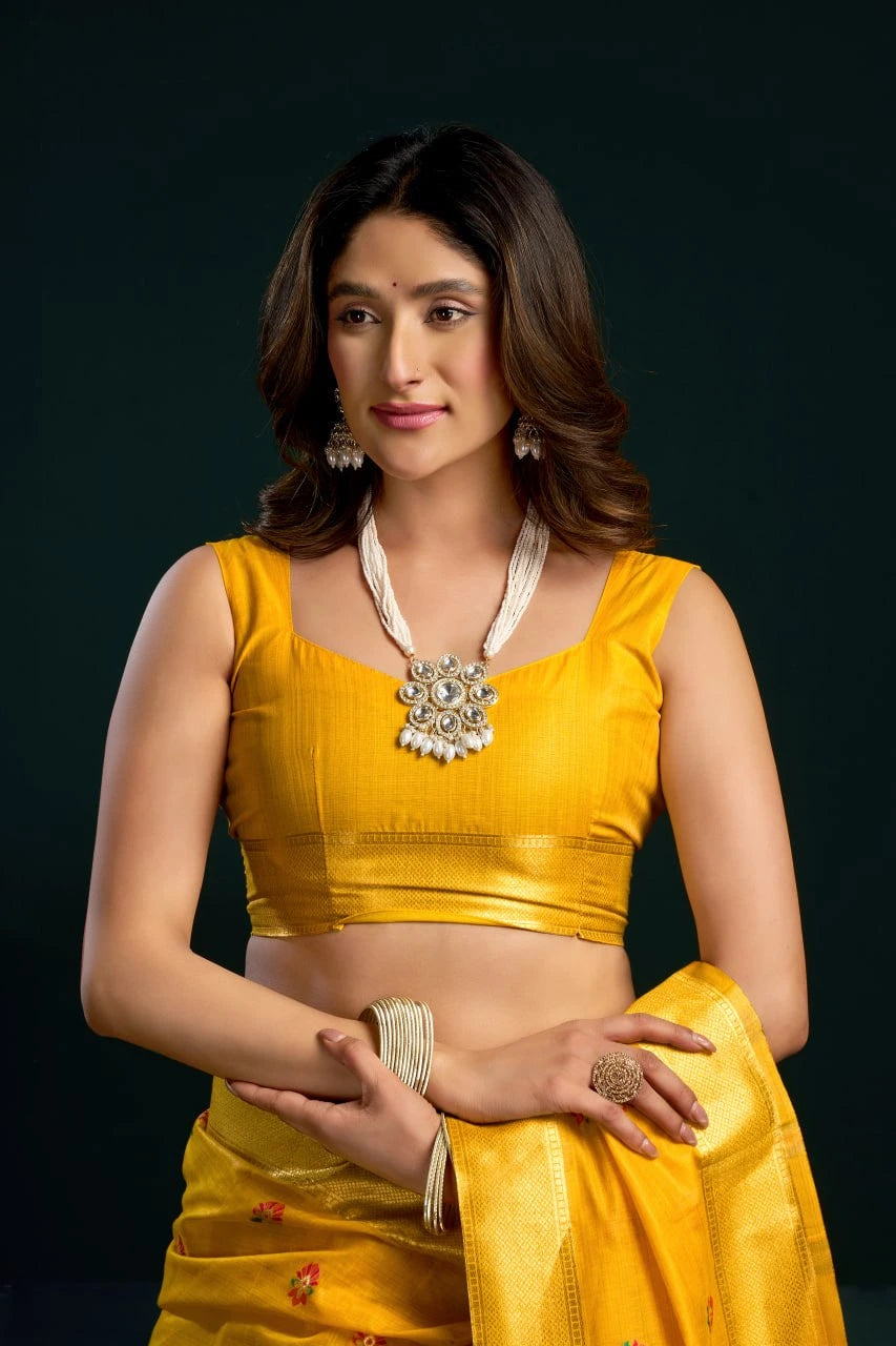 Woman in a yellow traditional outfit with jewelry against a dark background