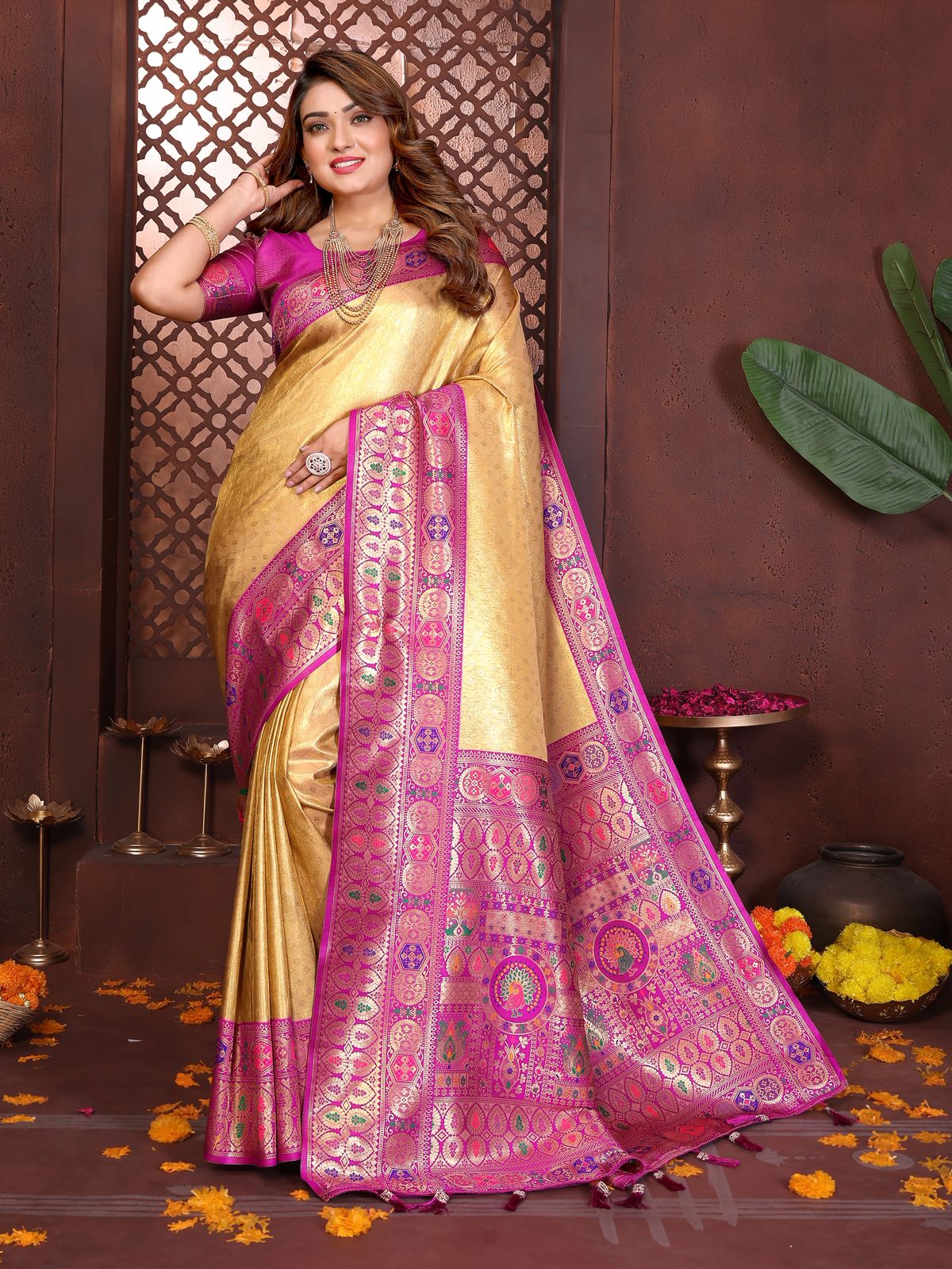 Woman wearing a traditional yellow and pink saree with intricate patterns against a decorative background.