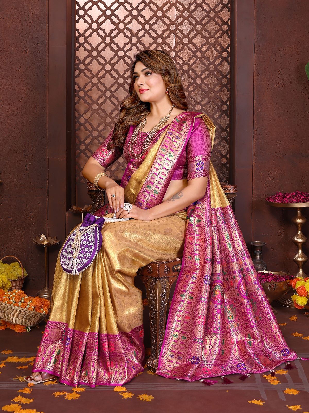 Woman in a traditional saree sitting on a decorative chair with a patterned wall in the background.