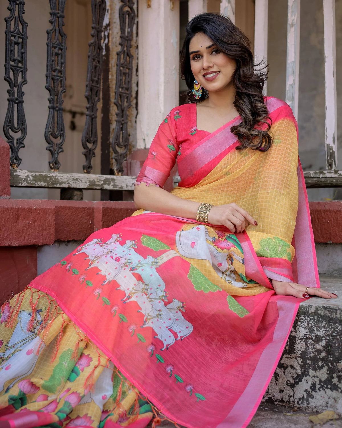Woman in a colorful saree sitting on steps with architectural elements in the background