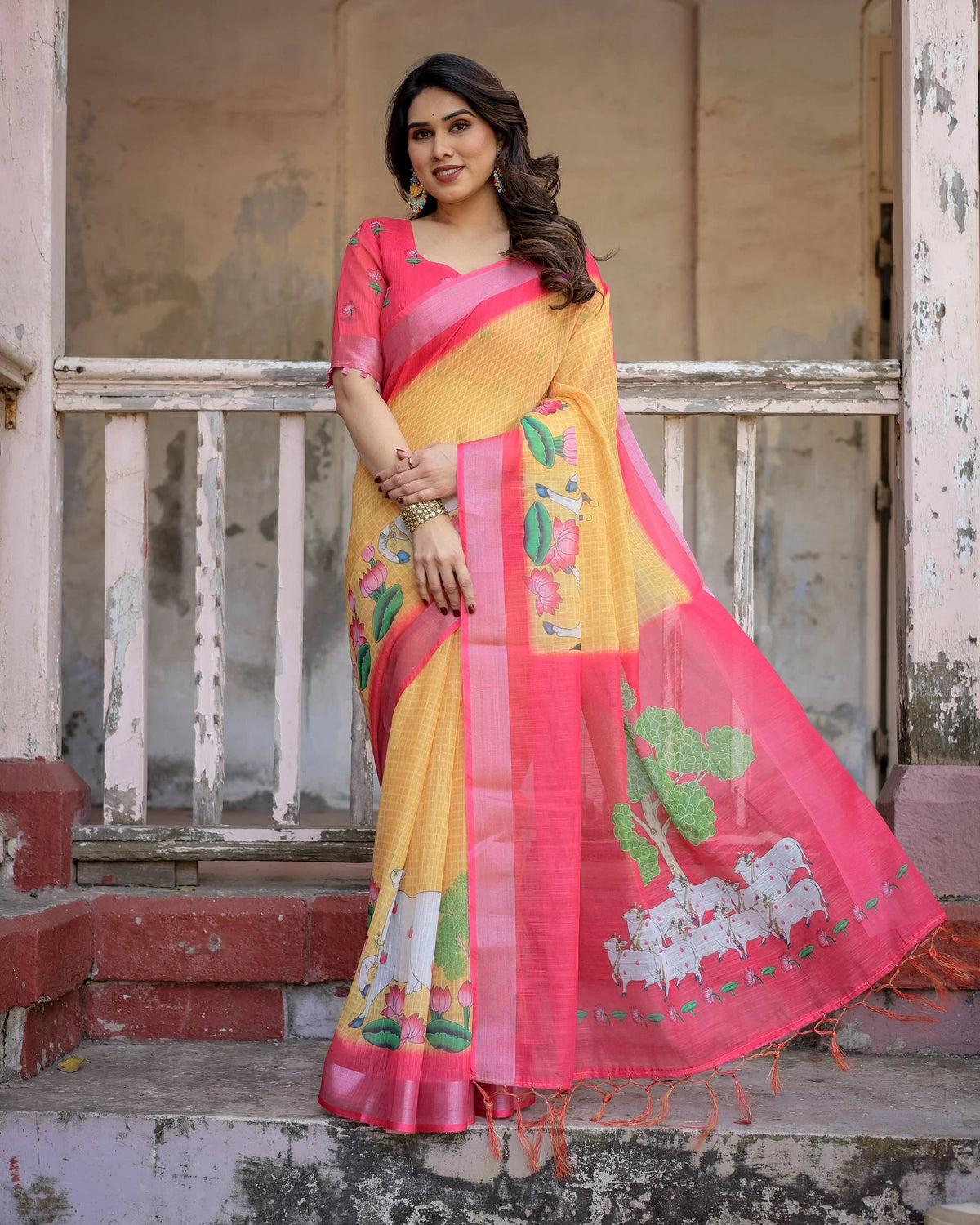 Woman wearing a yellow and pink saree with floral patterns on a rustic background