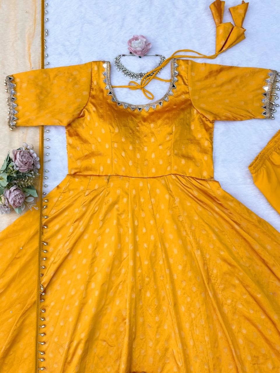 Yellow traditional outfit with silver detailing on a white background