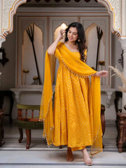 Woman in a yellow traditional outfit standing in an ornate room.
