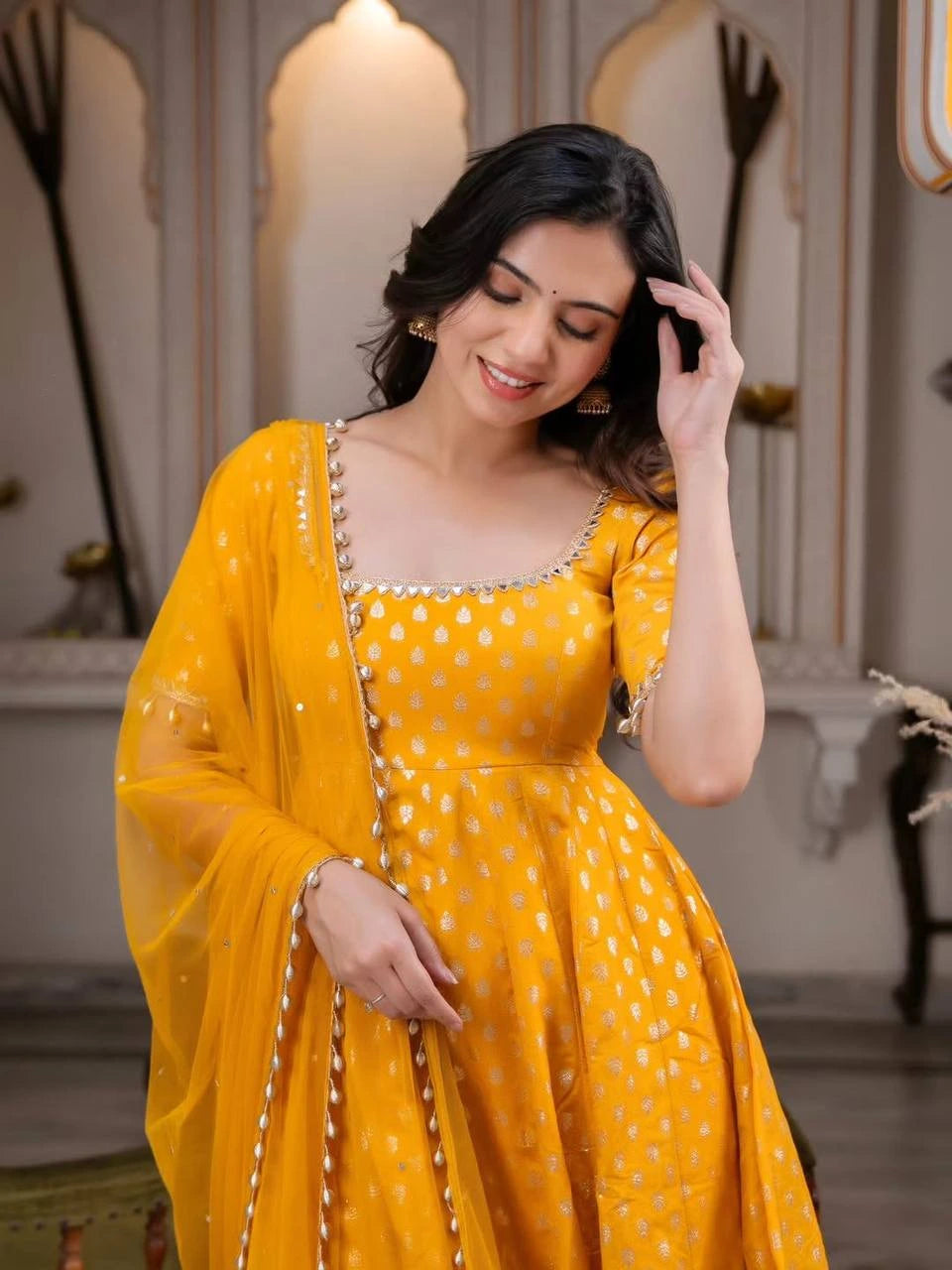 Woman wearing a yellow dress with a matching dupatta in an indoor setting