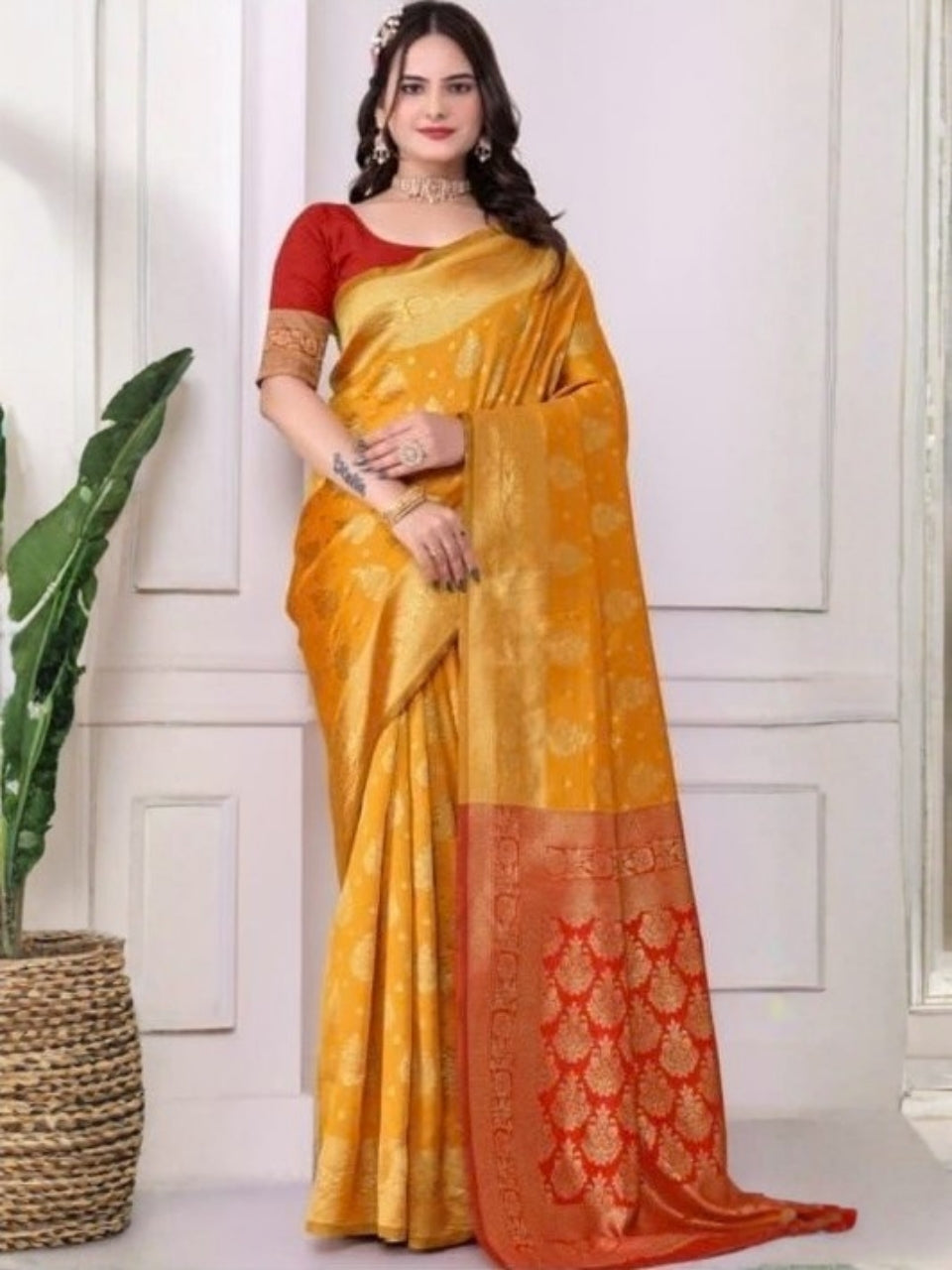 Woman wearing a yellow and red saree with a white wall background